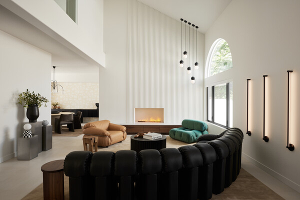 The designers painted the walls of the living room bright white and outfitted the space with custom millwork beneath the fireplace and modernist light fixtures and furniture.