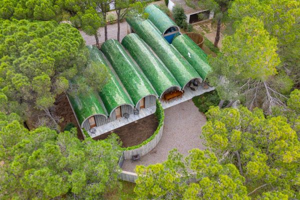 Designed by Bellafilarquitectes Studio, this residence in l’Escala features a striking curved roof clad with distinctive green tiles.