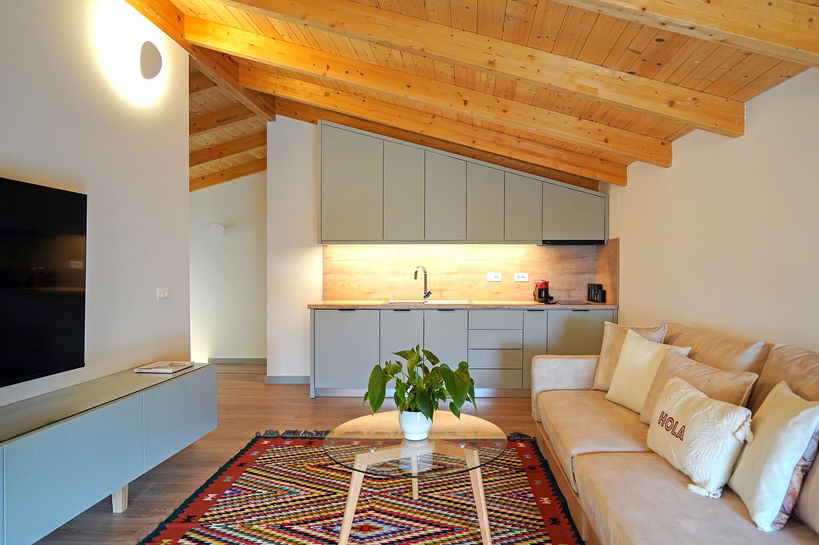 Situated underneath the wood ceiling, the upper-level apartment’s living room is elevated by a petite, functional kitchen.