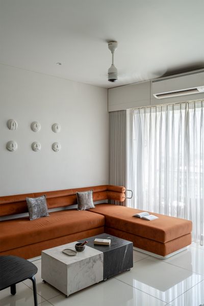 The home is filled with custom furniture, including this living room sectional sofa with wall-mounted back rests, and a coffee table clad in two shades of marble.