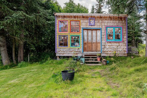 The remote property is a homesteader’s dream with three hand-built dwellings, a greenhouse, and nearly four acres of forested land.