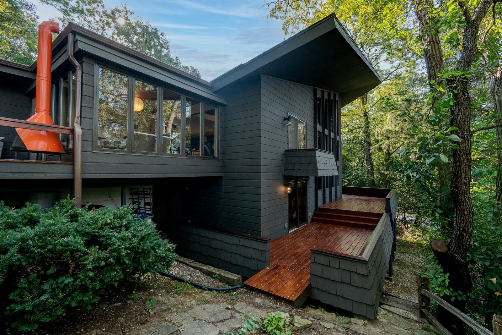 This midcentury getaway features a cozy conversation pit flanked by a massive wall of windows and a double-height fireplace.